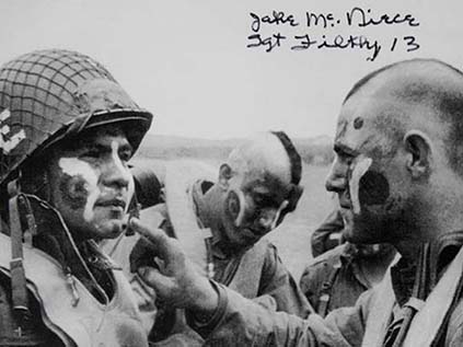 A paratrooper of the Filthy Thirteen applying war paint to another man face in England on the eve of D-Day