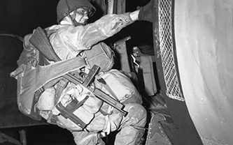 A paratrooper of the 101st Airborne Division in full jump equipment climbing aboard a C-47 transport plane